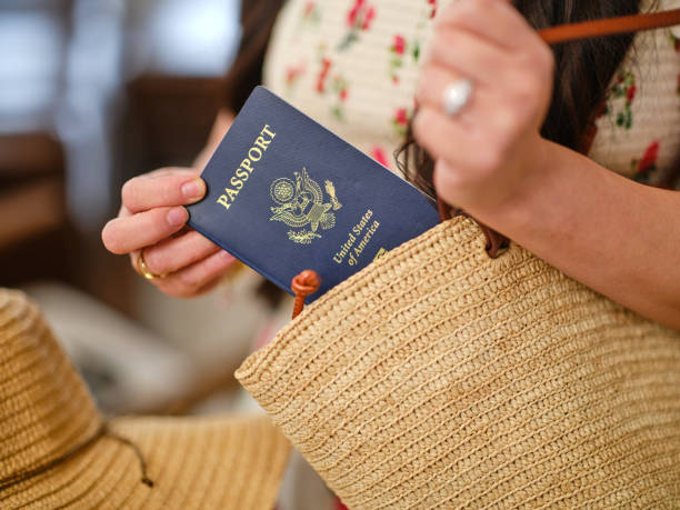 Woman holding a U.S. passport while placing it into a straw handbag, symbolizing travel readiness and passport services.